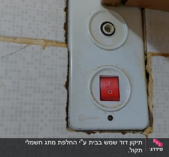 מתג חשמלי עם כפתור אדום על קיר